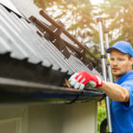 Red Robin Window Cleaning employee cleaning gutters by hand